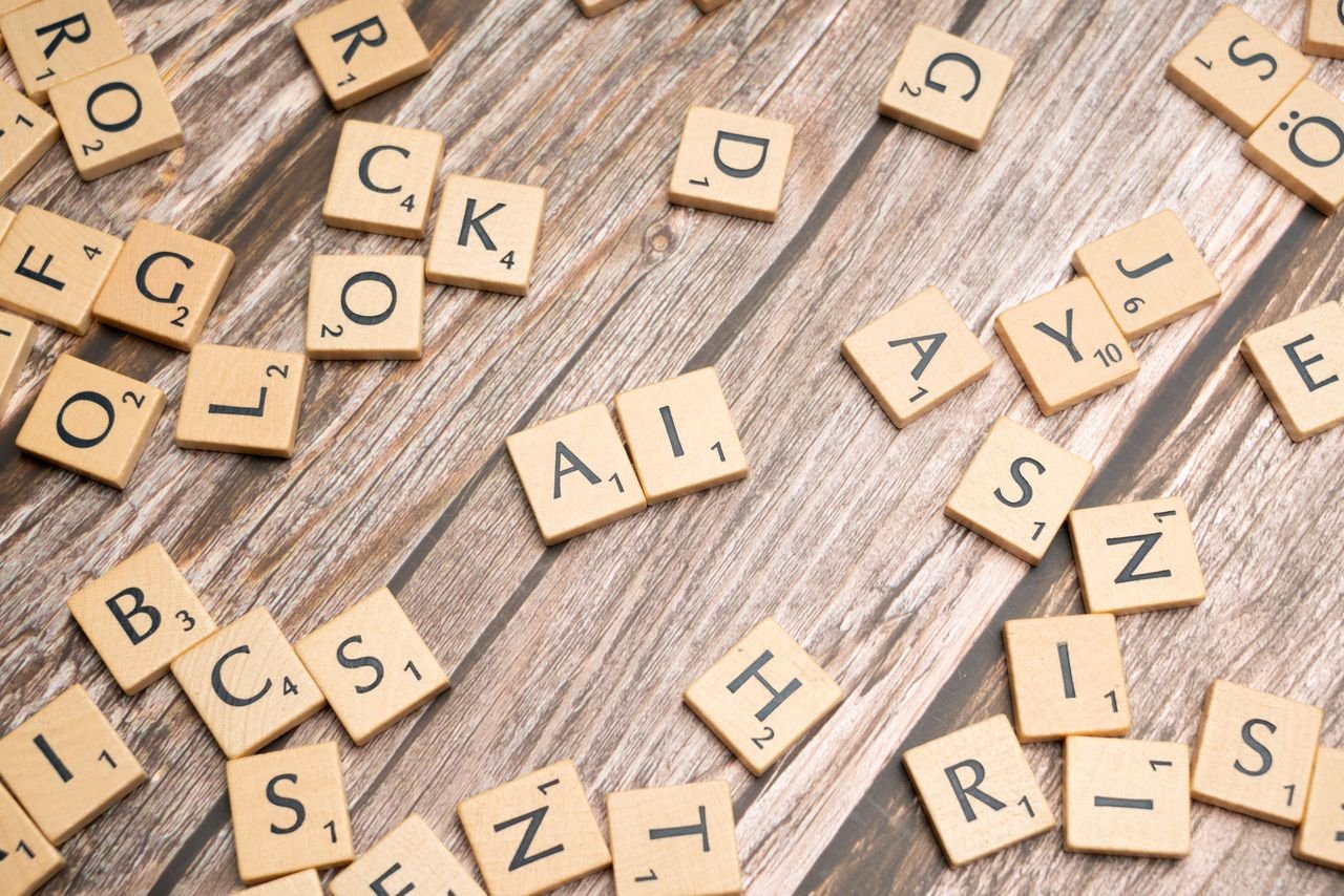 heros-img Wooden letter tiles scattered on a textured surface, spelling 'AI'.