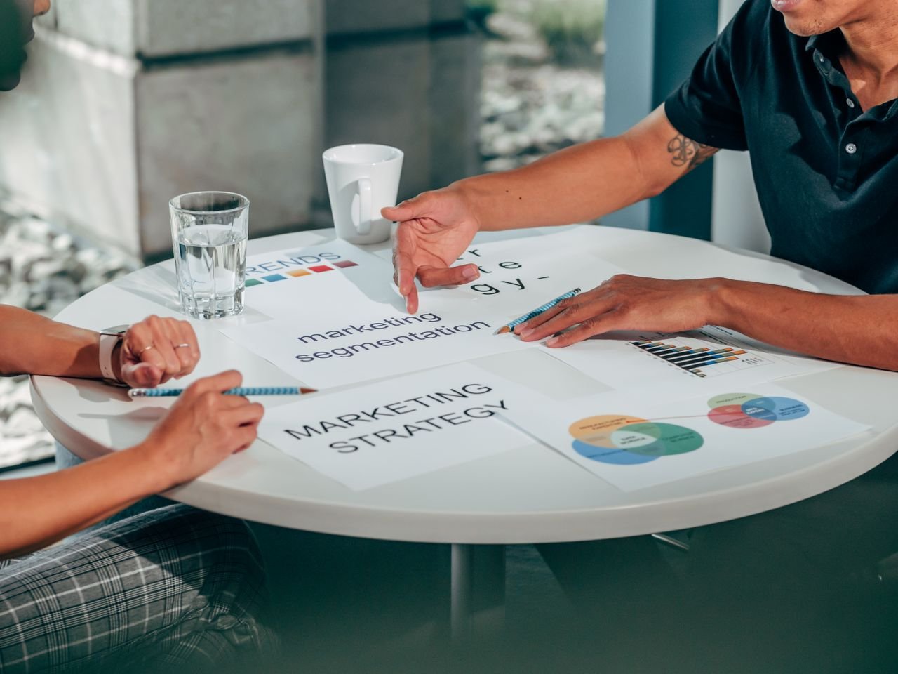 about-us Two adults in an office discussing marketing strategy around a round table.
