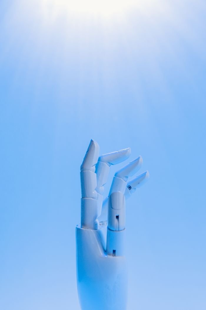services-02 A robotic hand reaching upward against a blue sky, symbolizing technology's future.